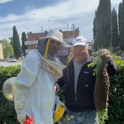 Filippo in tuta da apicoltore insieme al nonno che mostra uno sciame d'api